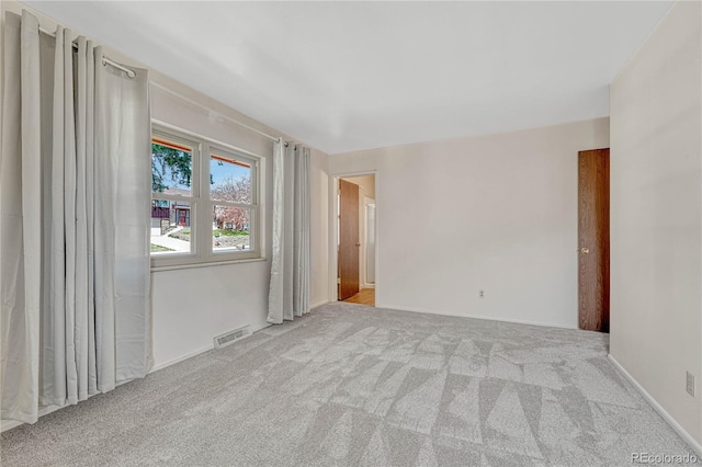 unfurnished room with carpet flooring, visible vents, and baseboards
