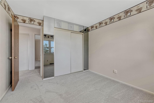 unfurnished bedroom featuring light carpet, baseboards, and a closet