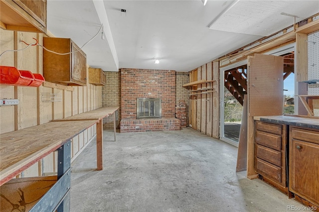 unfurnished living room featuring a brick fireplace and unfinished concrete flooring