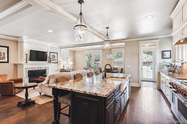 kitchen with pendant lighting, sink, a breakfast bar area, a kitchen island with sink, and light stone countertops