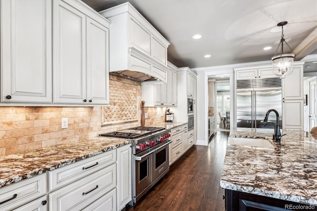 kitchen featuring pendant lighting, sink, white cabinetry, high quality appliances, and custom exhaust hood