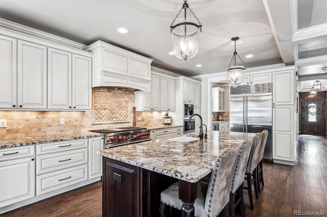 kitchen featuring pendant lighting, sink, a center island with sink, and white cabinets