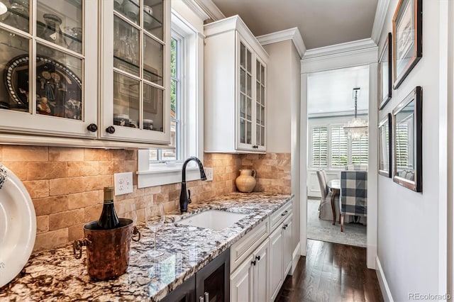 bar featuring sink, crown molding, backsplash, light stone counters, and white cabinets