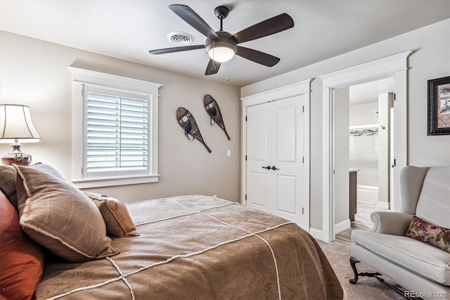 carpeted bedroom featuring ceiling fan, a closet, and ensuite bath