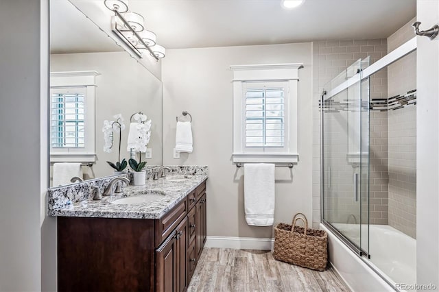 bathroom featuring vanity, hardwood / wood-style floors, and shower / bath combination with glass door