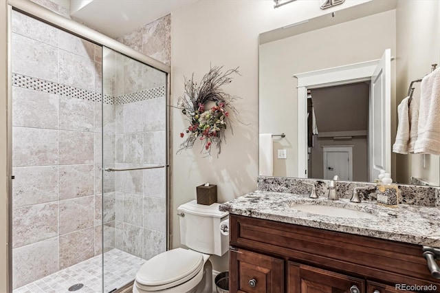 bathroom with a shower with door, vanity, and toilet