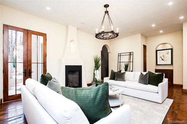 living room with hardwood / wood-style flooring, a chandelier, a fireplace, and french doors