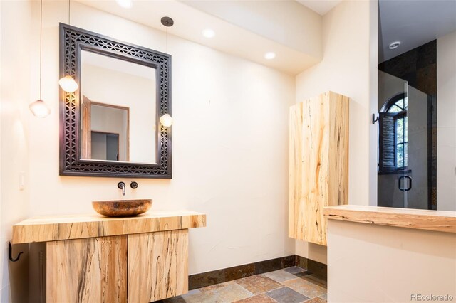 2435 S Milwaukee St, Denver, CO 80210 - bathroom with baseboards, vanity, stone tile flooring, recessed lighting, and a shower with door