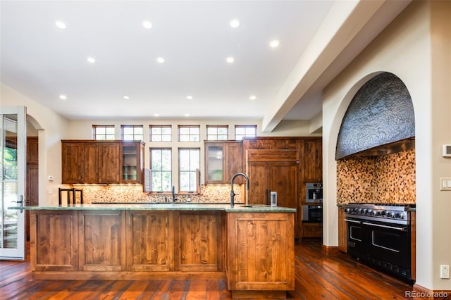 kitchen with a kitchen island with sink, a healthy amount of sunlight, and range with two ovens