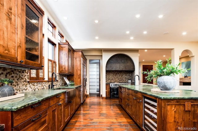 kitchen featuring sink, wine cooler, dark hardwood / wood-style floors, backsplash, and a center island with sink