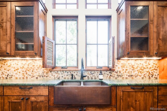 2435 S Milwaukee St, Denver, CO 80210 - kitchen with a sink, brown cabinets, glass insert cabinets, decorative backsplash, and light stone counters
