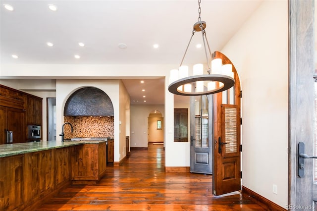 kitchen featuring sink, dark wood-type flooring, a chandelier, pendant lighting, and decorative backsplash