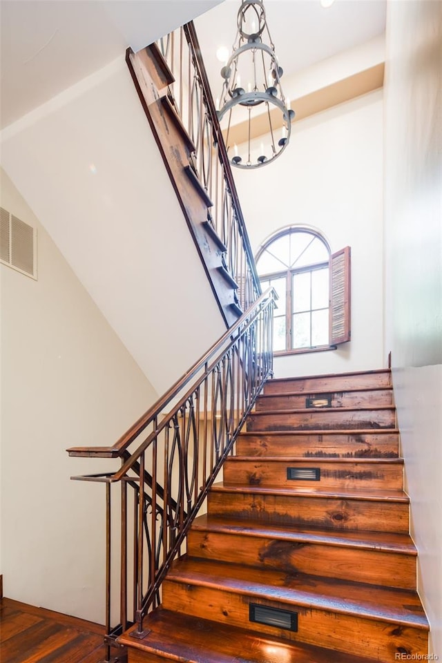 stairway featuring a notable chandelier and wood-type flooring