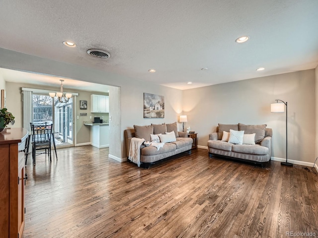 living room featuring a textured ceiling, dark hardwood / wood-style flooring, and a notable chandelier