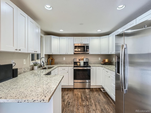 kitchen with white cabinetry, sink, stainless steel appliances, dark hardwood / wood-style flooring, and kitchen peninsula