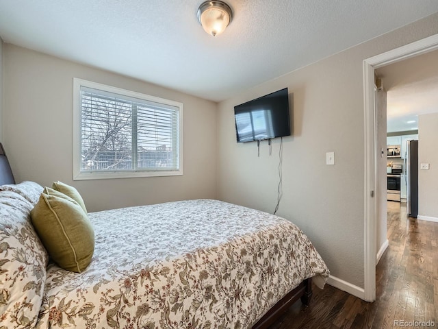 bedroom with stainless steel fridge and dark hardwood / wood-style floors