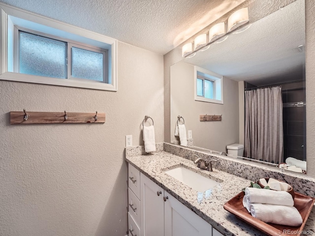 bathroom featuring vanity, a textured ceiling, toilet, and curtained shower