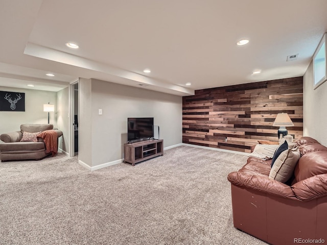 carpeted living room featuring wood walls