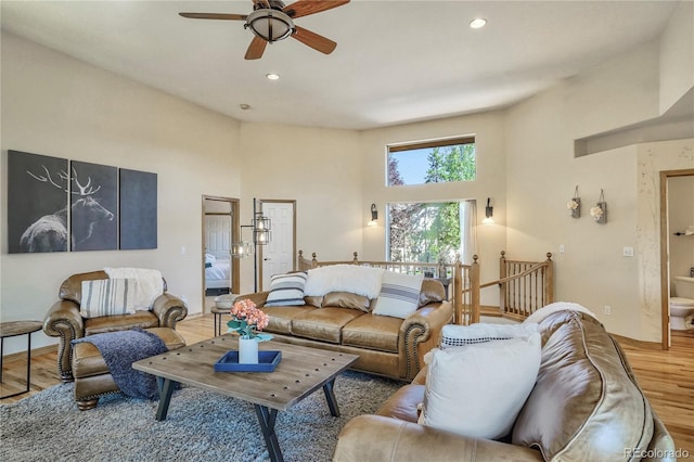 living room featuring hardwood / wood-style flooring, ceiling fan, and a high ceiling