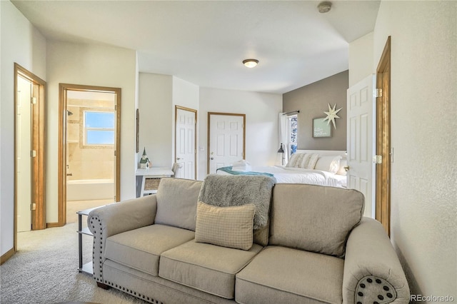 bedroom featuring ensuite bath and light carpet