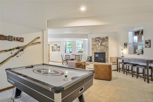 recreation room featuring light colored carpet and a stone fireplace