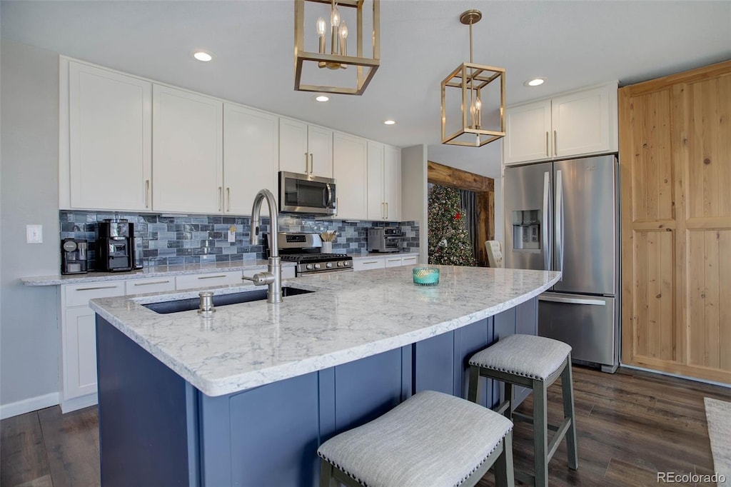 kitchen with pendant lighting, an island with sink, and appliances with stainless steel finishes