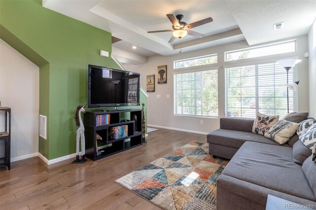 living room featuring a textured ceiling, ceiling fan, hardwood / wood-style floors, and a tray ceiling