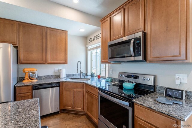 kitchen featuring stone counters, light hardwood / wood-style flooring, appliances with stainless steel finishes, and sink