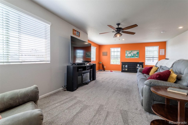 living area with light carpet, ceiling fan, and baseboards