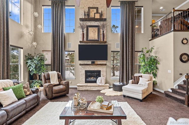 living room featuring carpet flooring, a fireplace, a healthy amount of sunlight, and a high ceiling