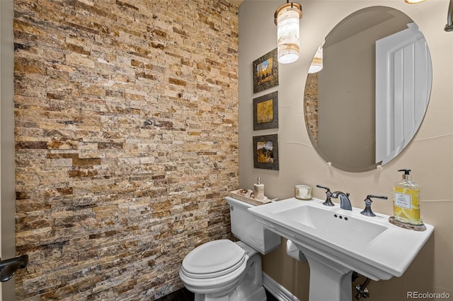 bathroom with brick wall, sink, and toilet