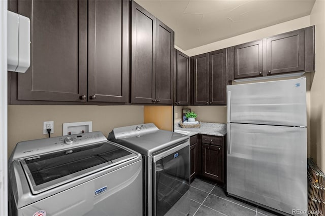 clothes washing area featuring cabinets, dark tile patterned flooring, and independent washer and dryer