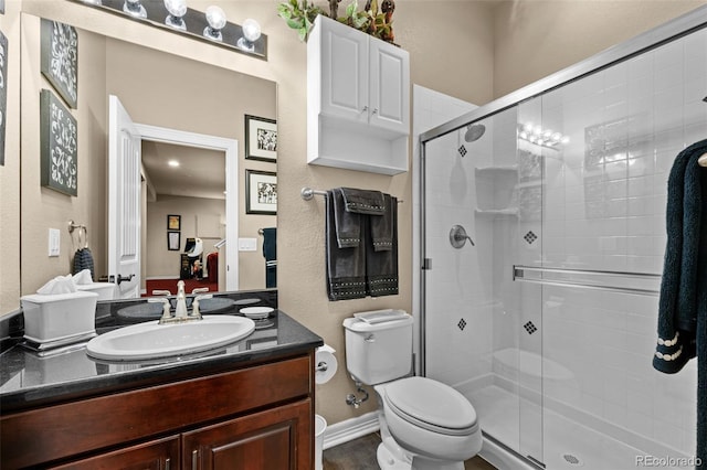 bathroom featuring vanity, toilet, and a shower with door