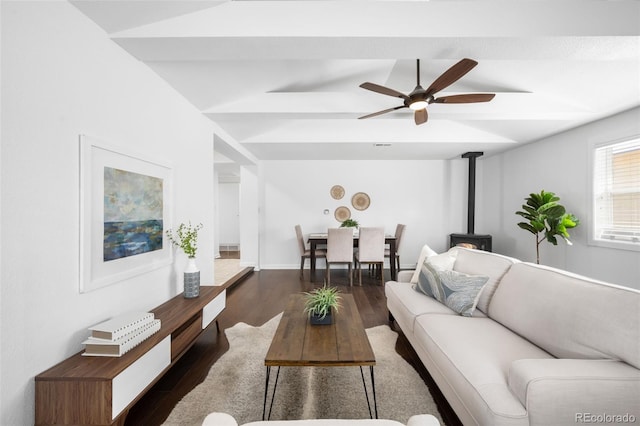 living area featuring lofted ceiling, a ceiling fan, dark wood-style floors, and a wood stove