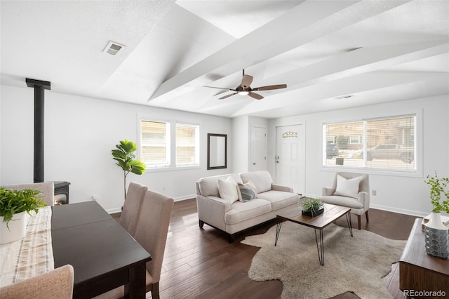 living area featuring visible vents, dark wood-type flooring, baseboards, lofted ceiling, and a wood stove