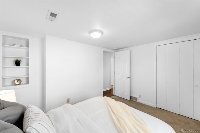 carpeted bedroom featuring baseboards, visible vents, and a closet