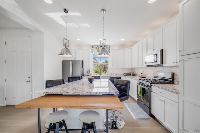 5280 Genoa St, Denver, CO 80249 - kitchen with stainless steel appliances, light wood-style floors, a center island, backsplash, and recessed lighting