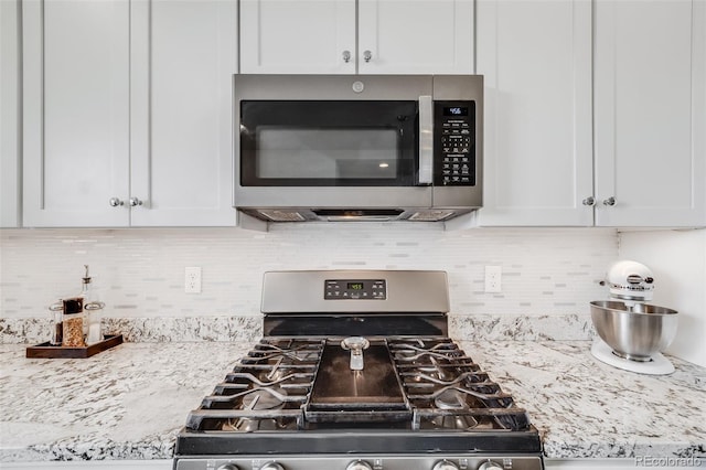 5280 Genoa St, Denver, CO 80249 - kitchen view of appliances with stainless steel finishes, white cabinetry, and light stone counters