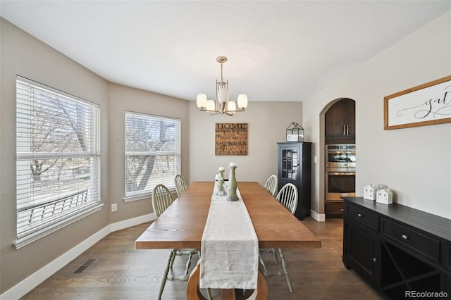 dining area featuring arched walkways, visible vents, a notable chandelier, and wood finished floors