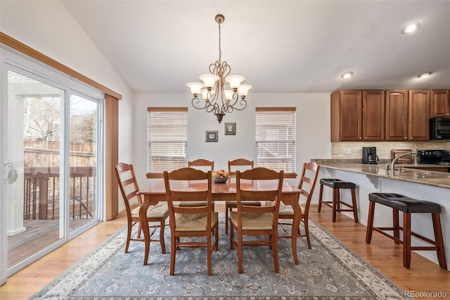 dining room featuring vaulted ceiling, recessed lighting, light wood-type flooring, and a chandelier