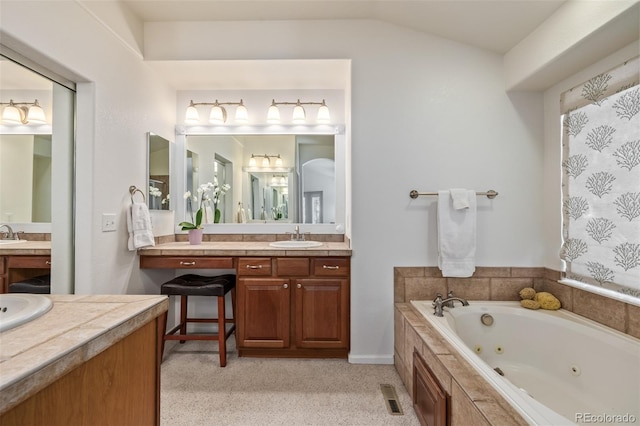 full bathroom featuring visible vents, two vanities, a sink, a jetted tub, and lofted ceiling