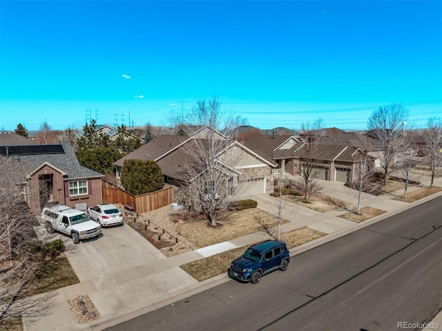 view of front of home featuring a residential view, concrete driveway, a garage, and fence