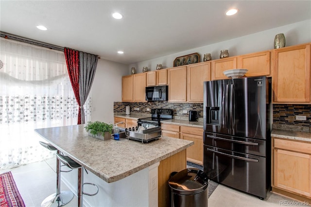 kitchen featuring black appliances, a center island, light brown cabinets, a kitchen breakfast bar, and backsplash