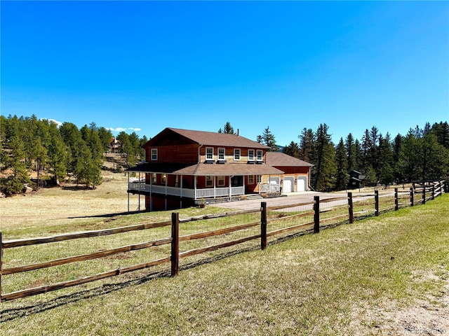 view of yard featuring covered porch, fence, driveway, and a garage