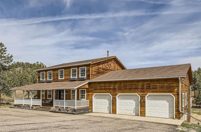 view of front facade with a garage, a porch, and aphalt driveway