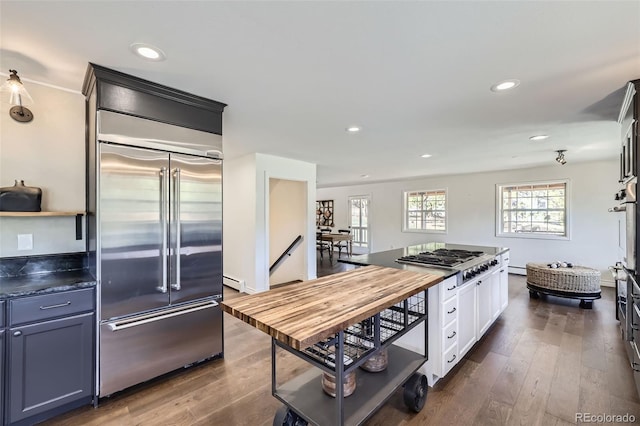 kitchen featuring baseboard heating, recessed lighting, white cabinets, dark wood finished floors, and appliances with stainless steel finishes