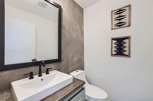 bathroom featuring vanity, toilet, and visible vents