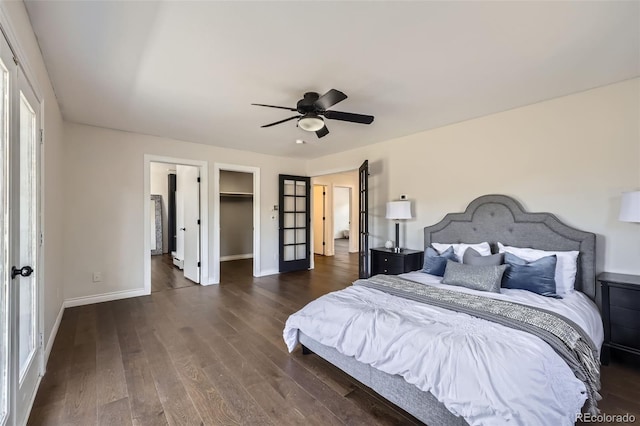 bedroom featuring baseboards, ceiling fan, a spacious closet, and dark wood-type flooring