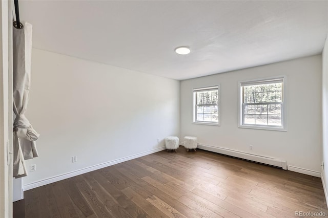 unfurnished room featuring dark wood-type flooring, baseboards, and a baseboard heating unit