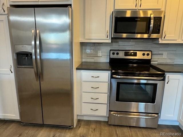 kitchen with white cabinets, tasteful backsplash, stainless steel appliances, and wood-type flooring